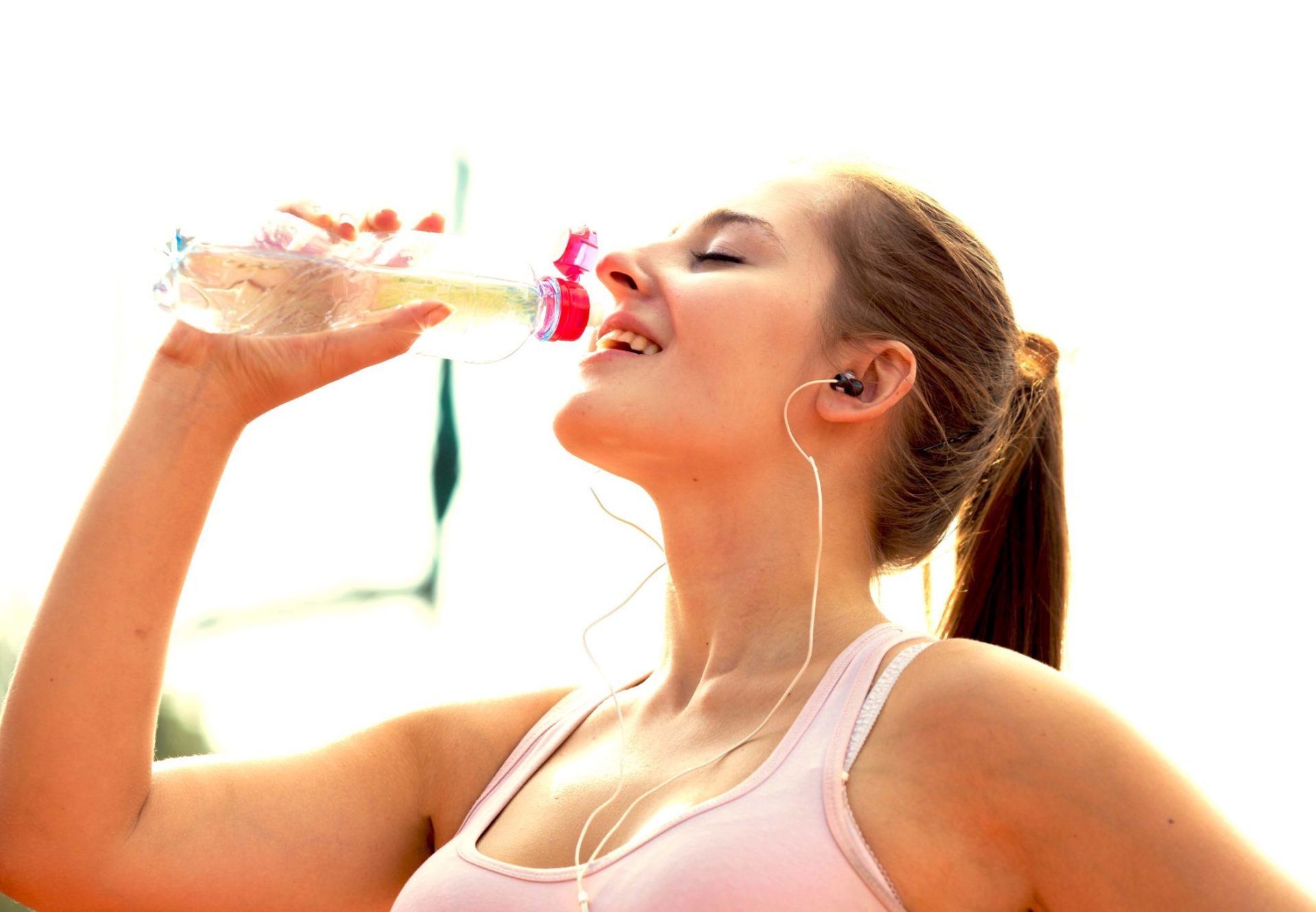 Woman drinking sports beverage with tethered closure