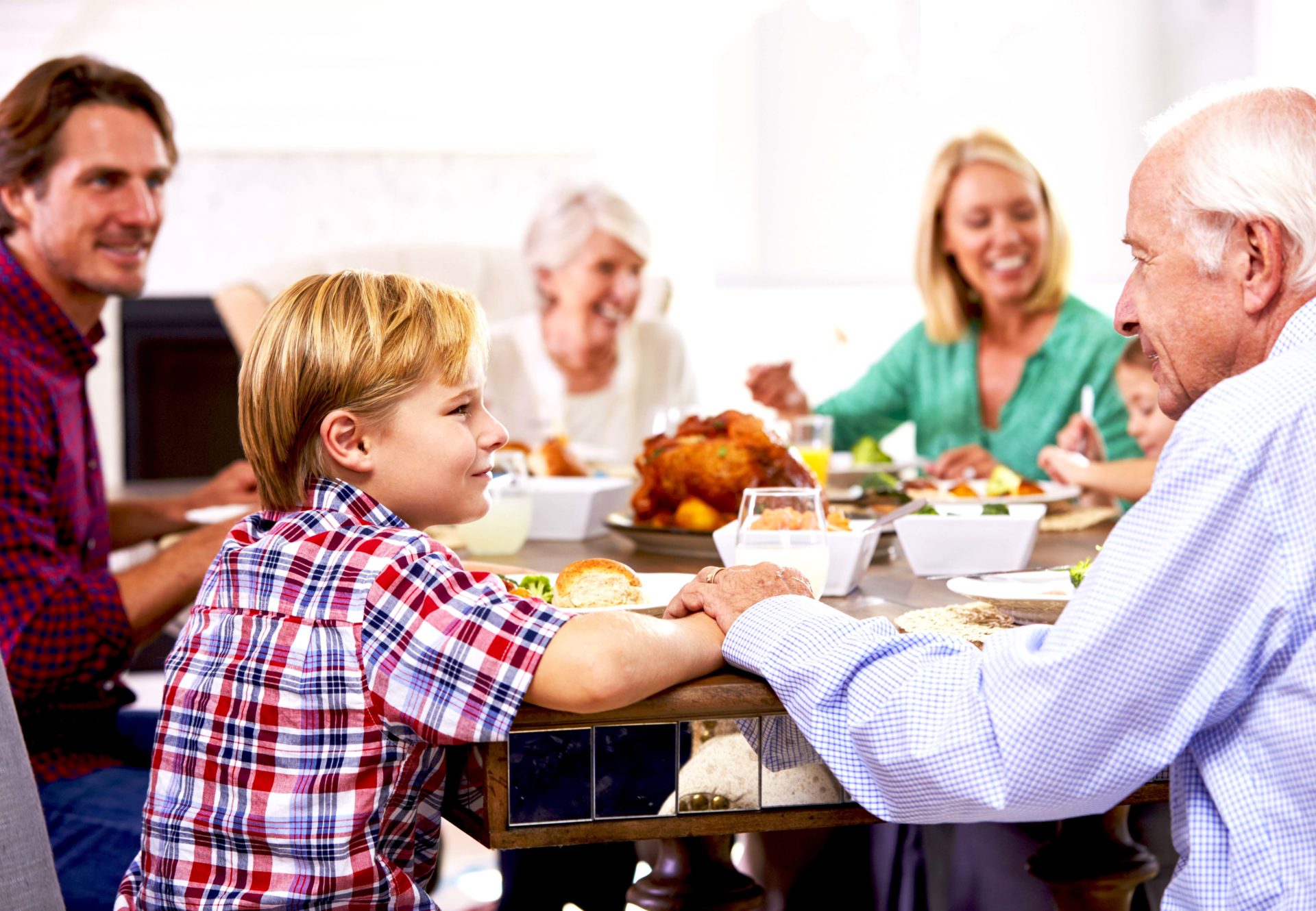 Family seated around dining room table prepared to eat a meal