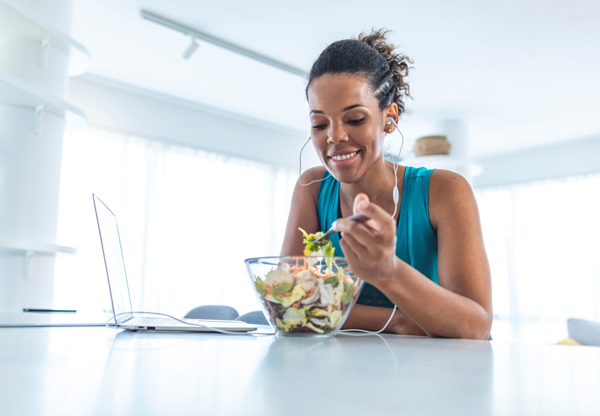 Woman eating a salad in white kitchen
